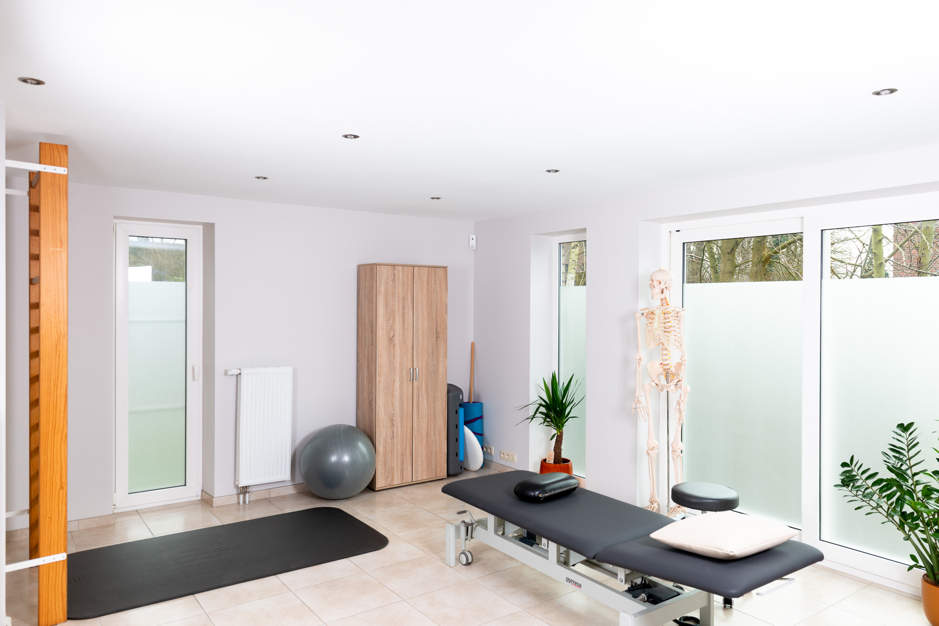 Cabinet de kinésithérapie de Lynn V. avec de gauche à droite, un espalier, un tapis, du matériel de kiné et une table de massage